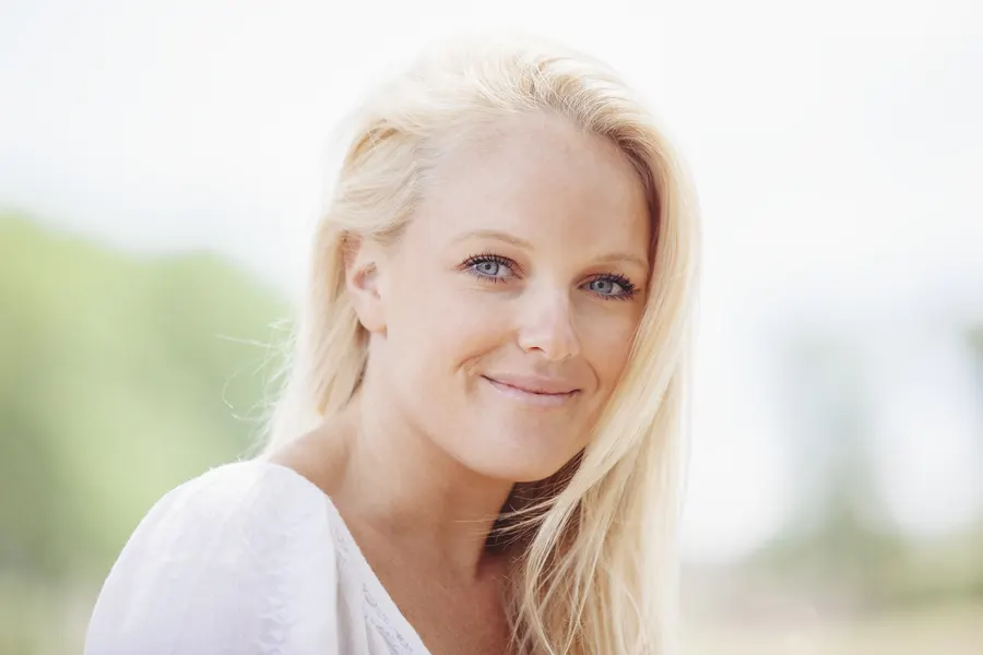 A beautiful blond woman smiling in soft outdoor