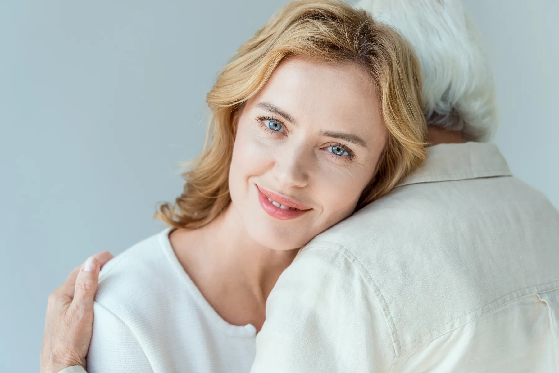 A blonde woman embraces person with gray hair