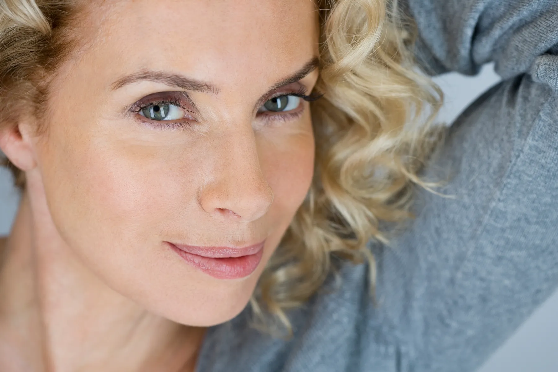 A blonde woman posing with hand behind head