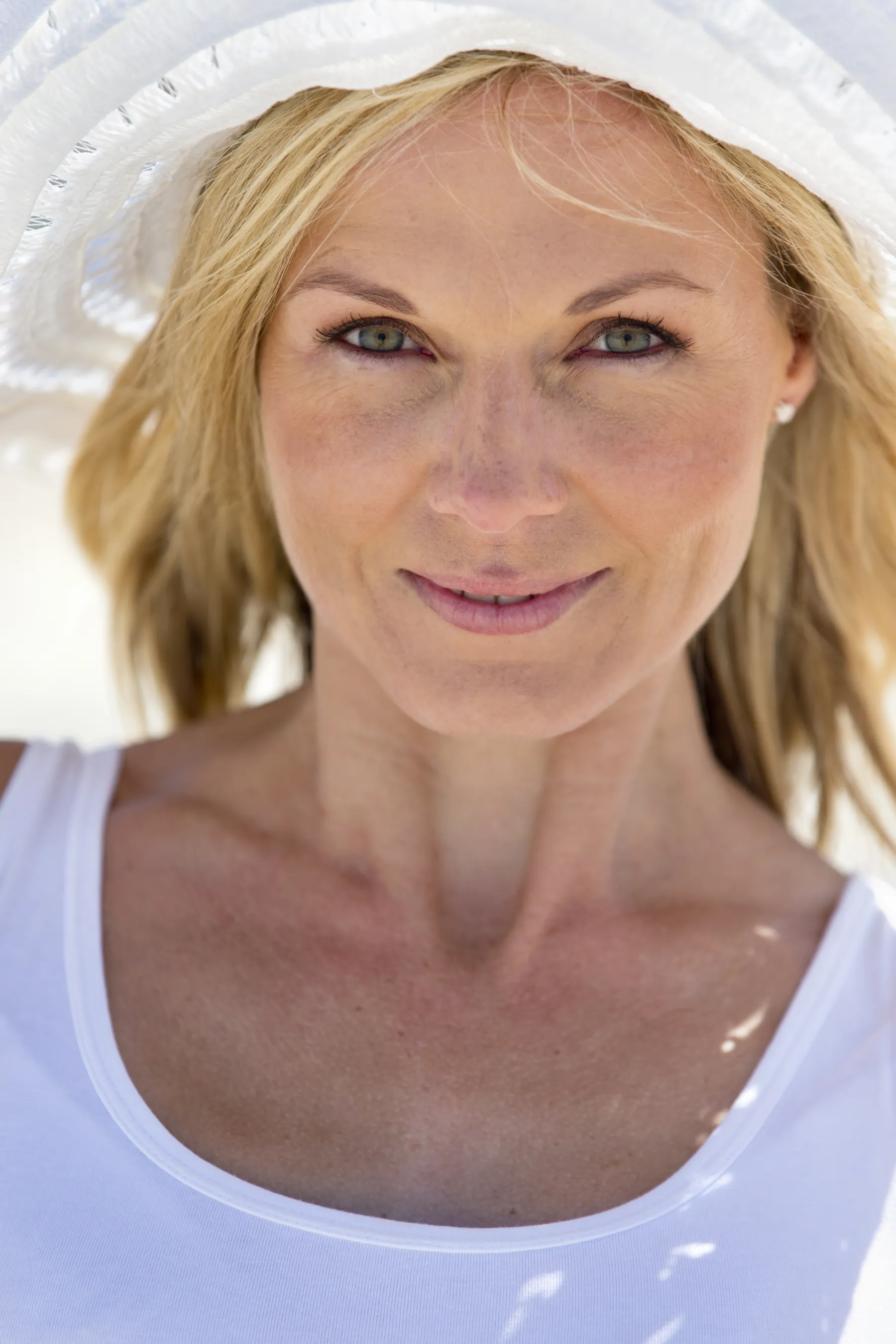 A blonde woman wearing a white hat smiling