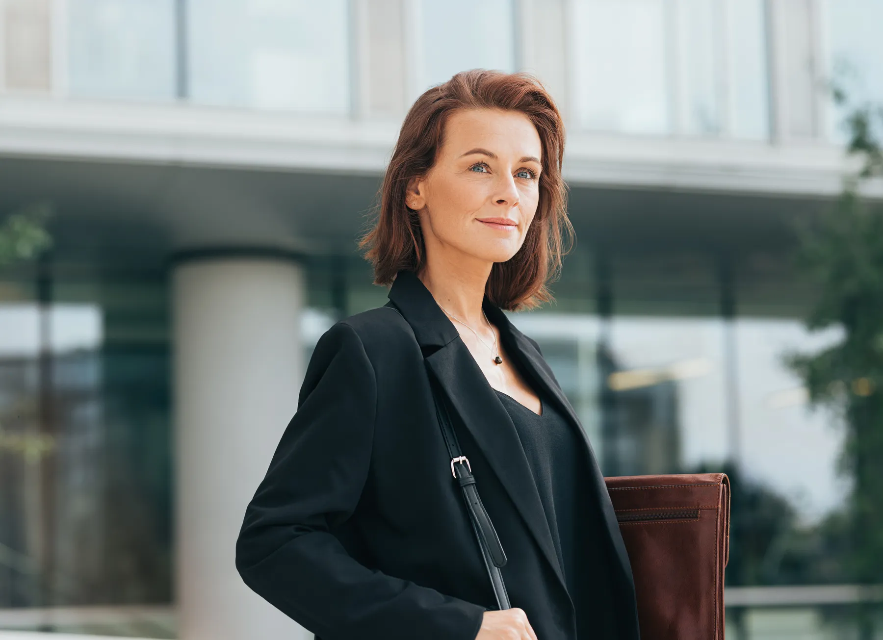 A confident woman in blazer with shoulder bag