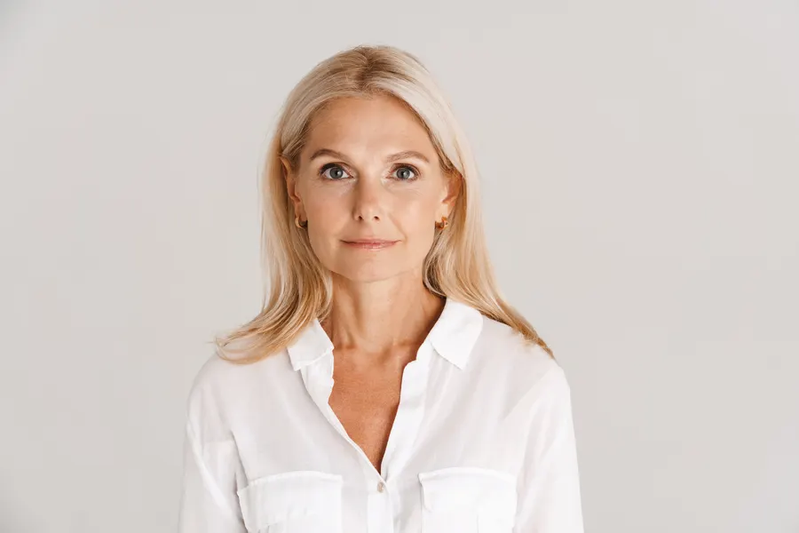 An elegant woman poses in white shirt indoors