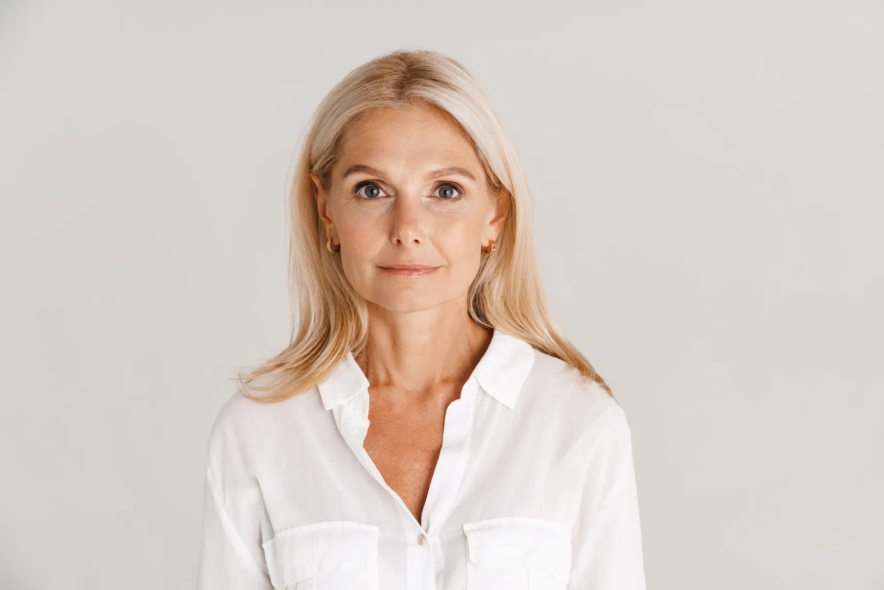 An elegant woman poses in white shirt indoors