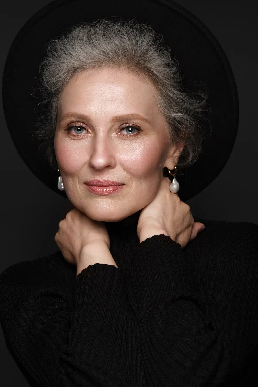 An elegant woman posing with black hat and earrings