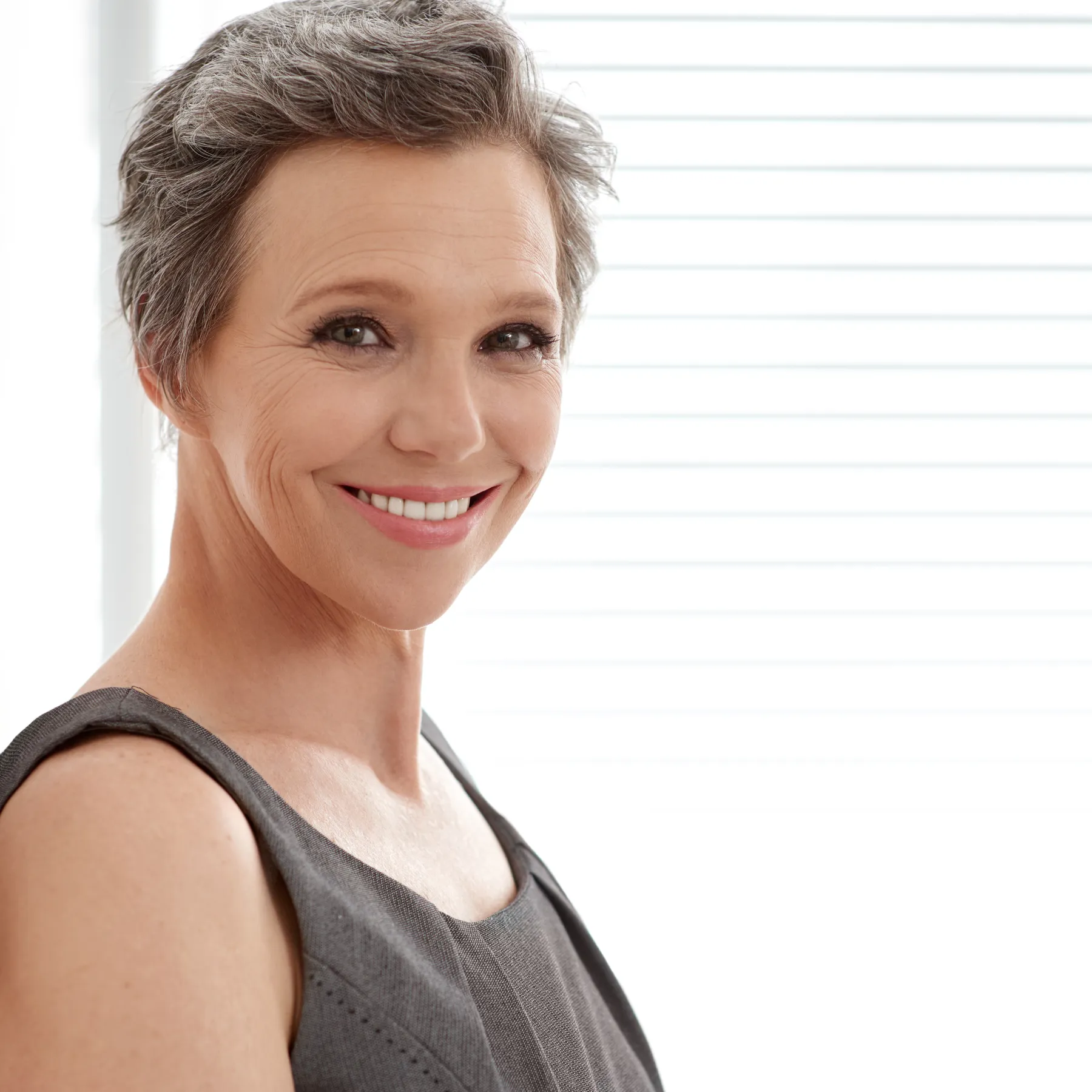 An elegant woman smiling with short grey hair