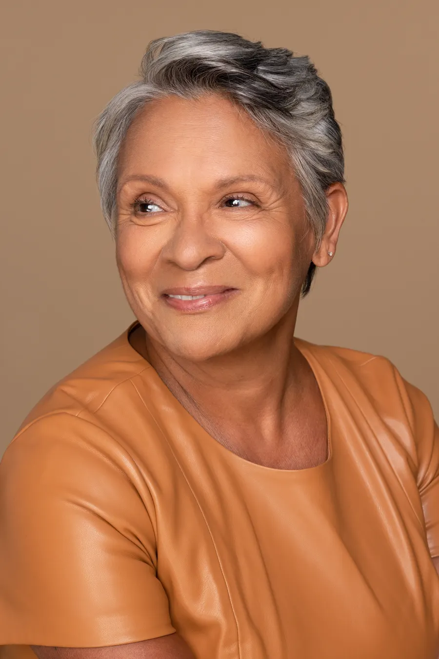 An elegant woman with gray hair and amber top