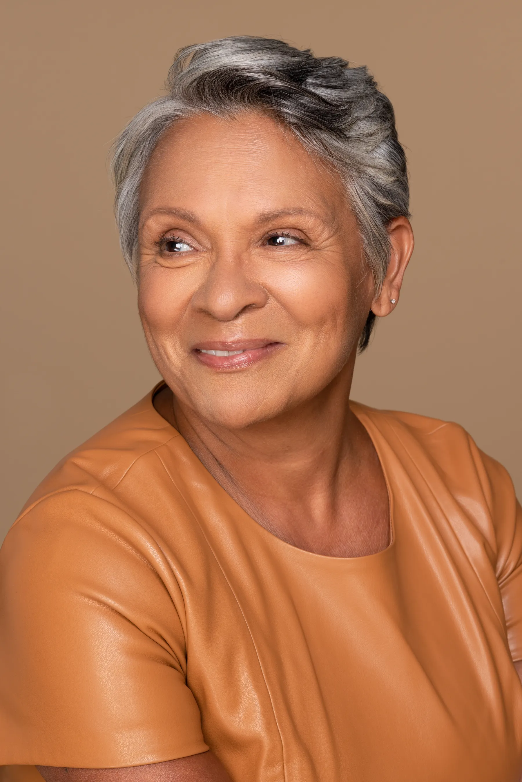 An elegant woman with gray hair and amber top