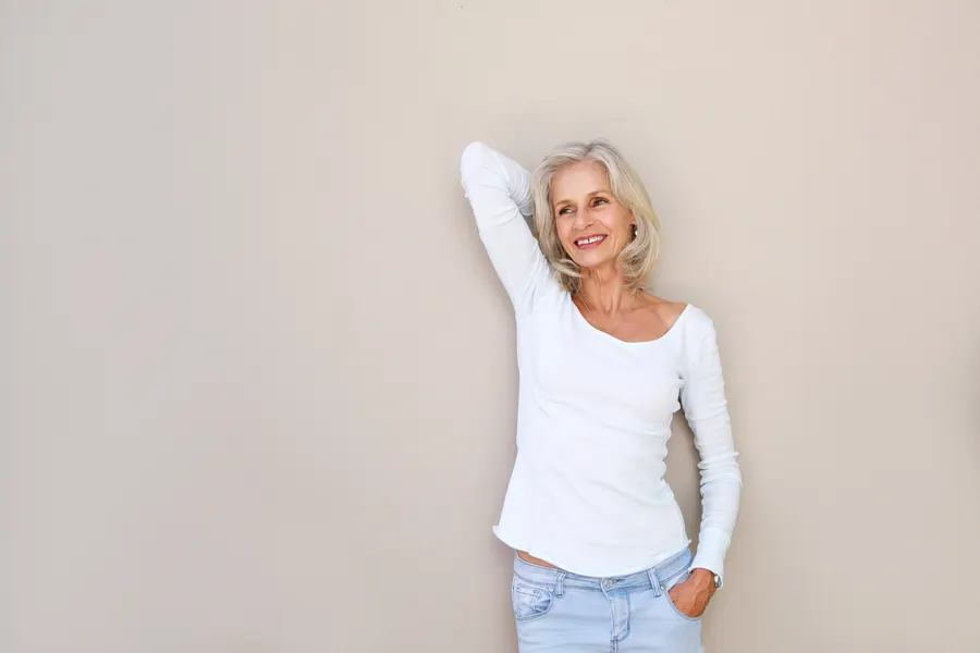 A happy mature woman in jeans and top posing