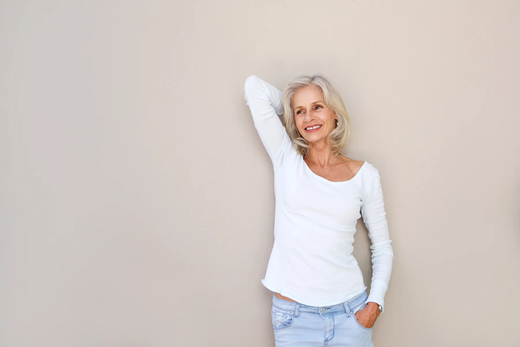 A happy mature woman in jeans and top posing