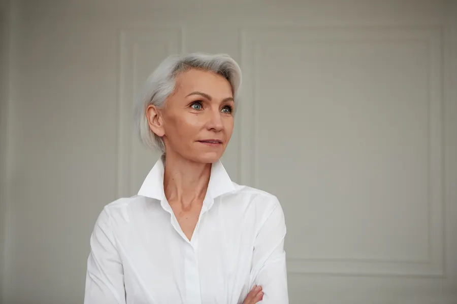 A mature woman poses in white shirt indoors