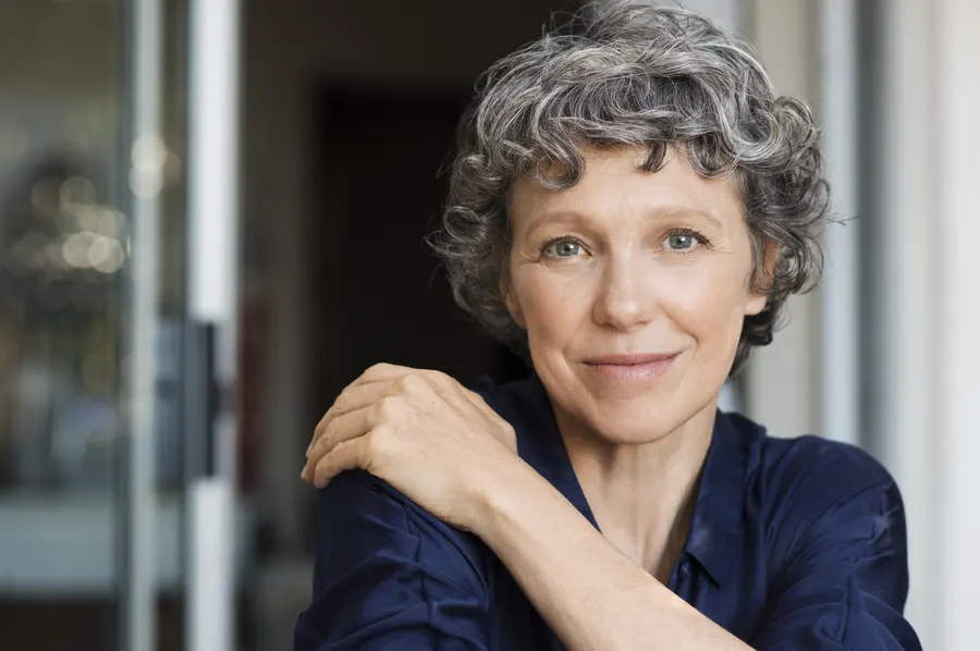 A mature woman with curly gray hair posing in