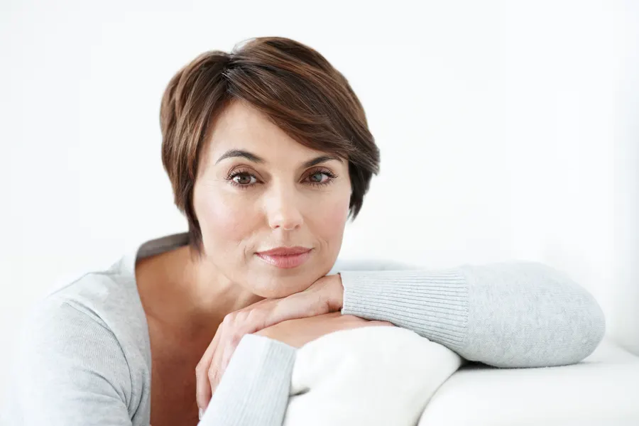 A mature woman with short brown hair posing indoors