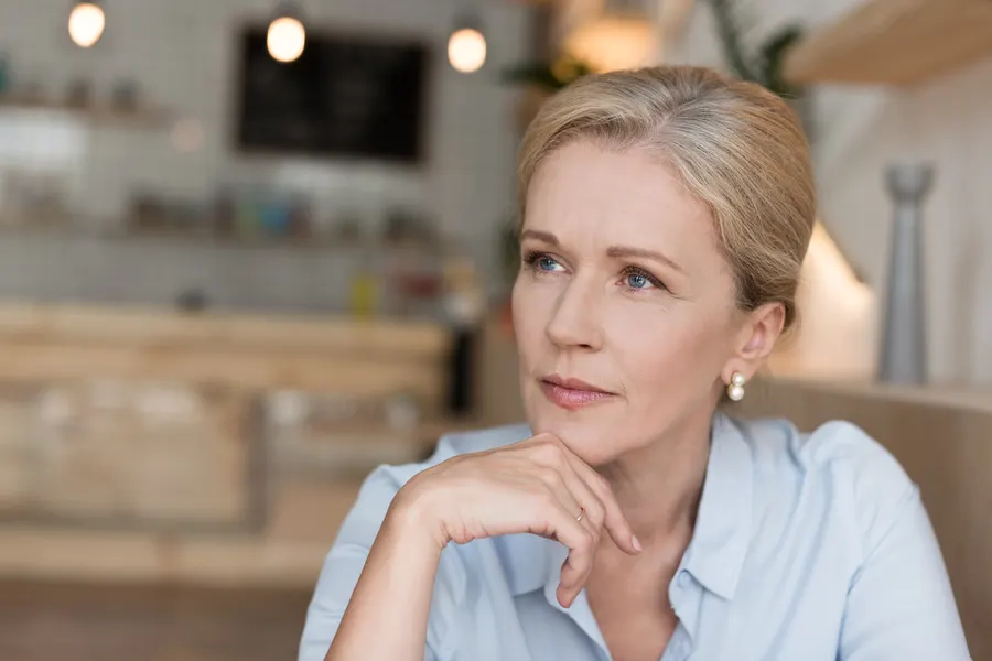 A pensive woman with hand to chin indoors