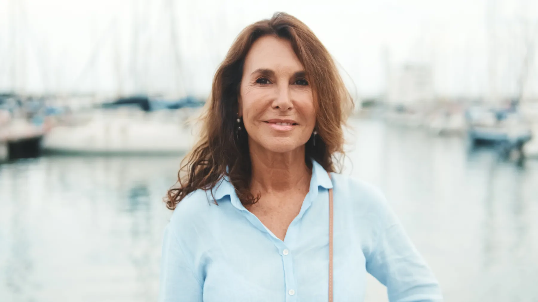 A relaxed woman by boats in a calm harbor