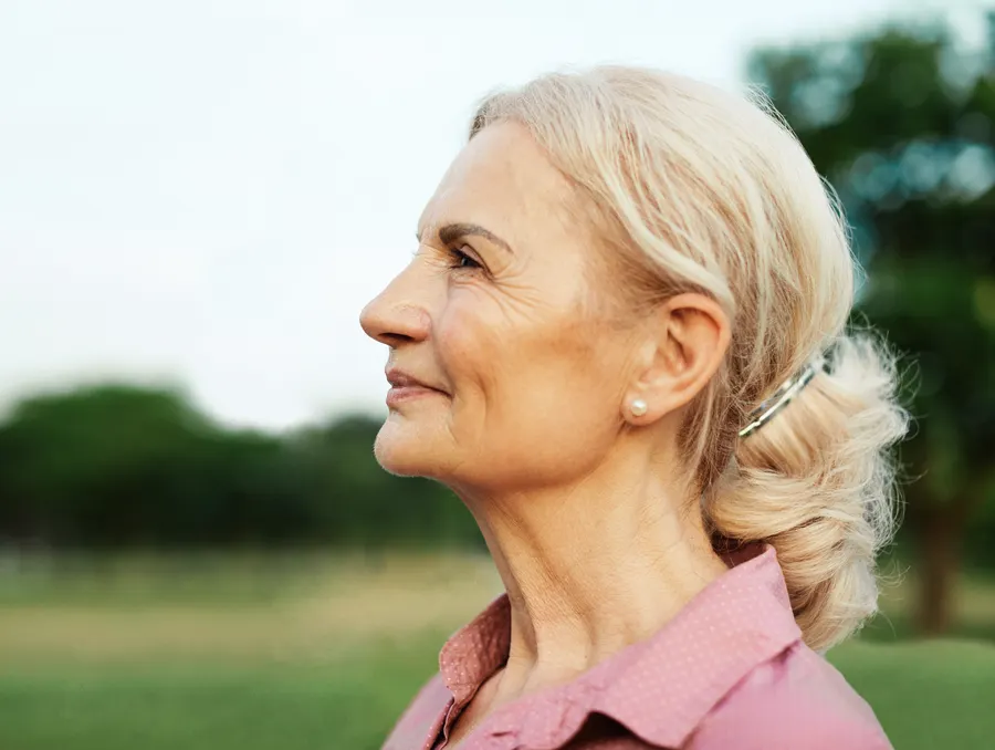 A senior woman profile with hair up outside
