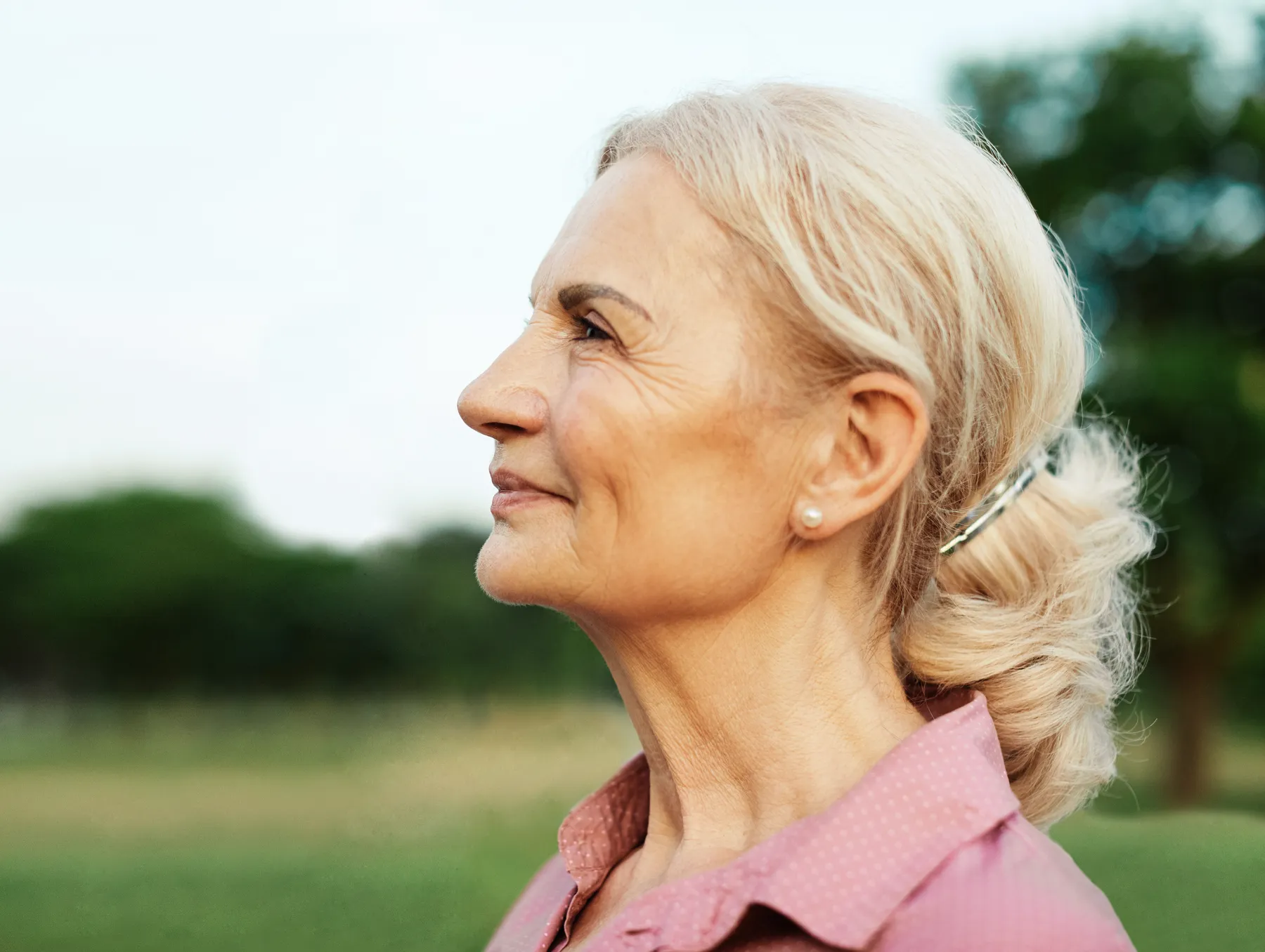 A senior woman profile with hair up outside