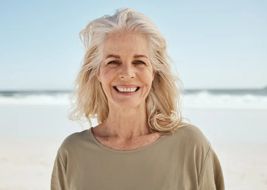 A senior woman smiling on a bright beach day