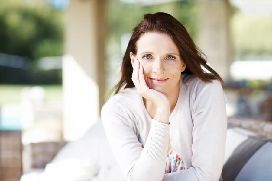 A serene woman relaxing on patio with calm smile