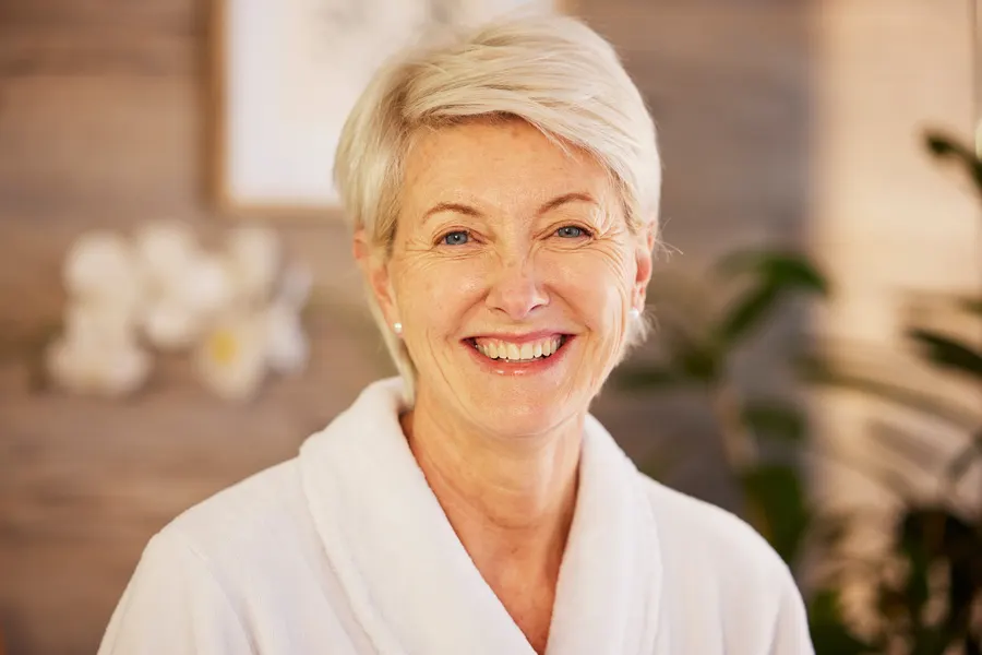 A smiling woman in bathrobe with short blonde hair