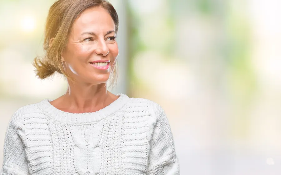 A smiling woman in sweater looking away from camera