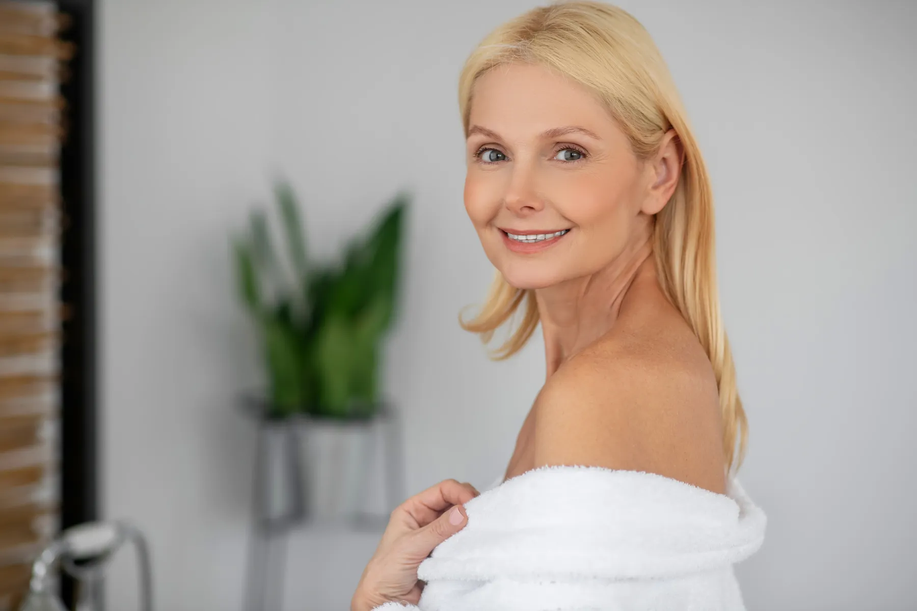 A smiling woman in white robe indoors