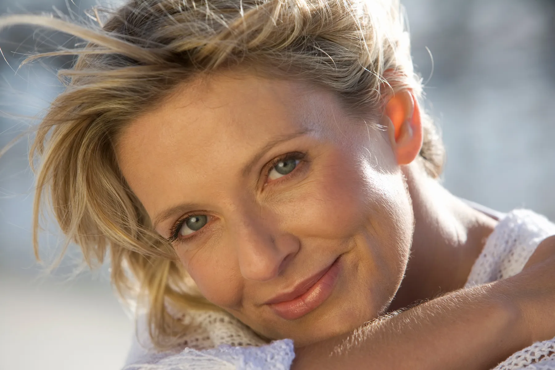 A smiling woman portrait with blonde hair and wind