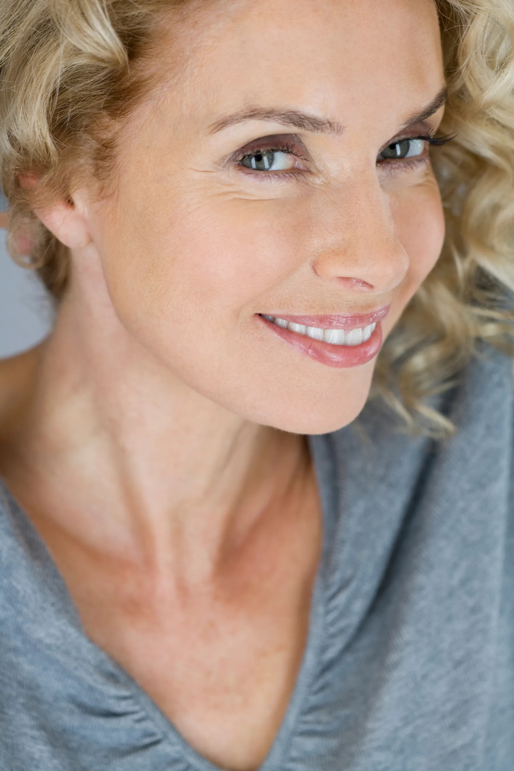 A smiling woman posing with blond curly hair