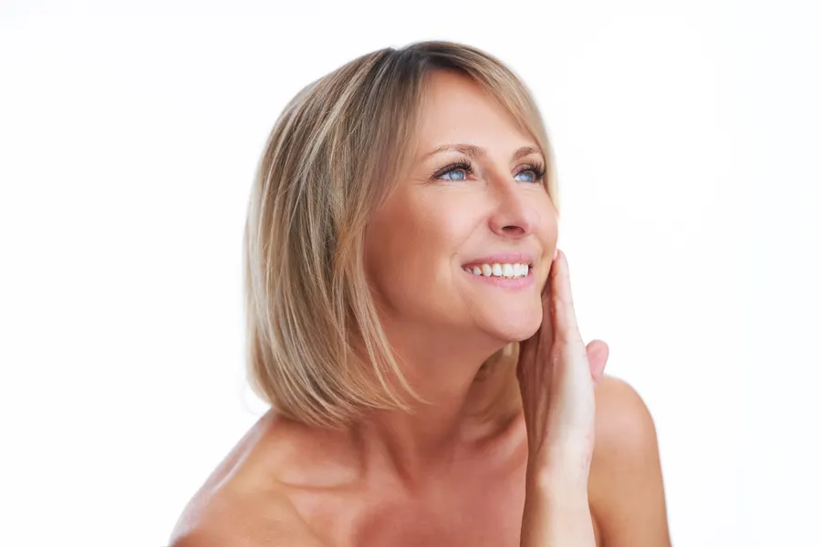 A smiling woman posing with hand on face