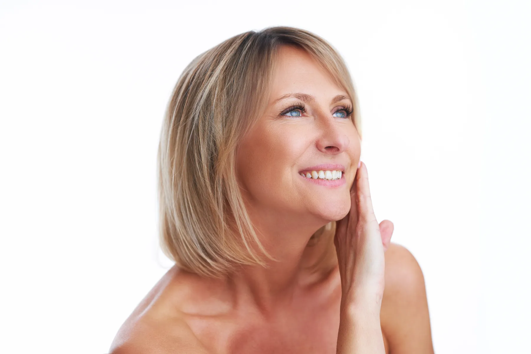A smiling woman posing with hand on face