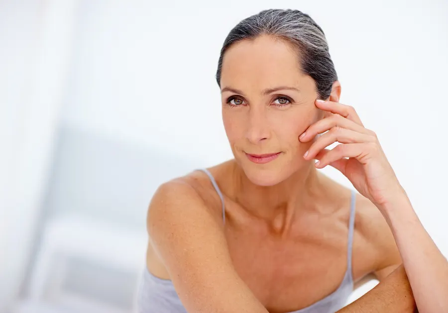 A smiling woman posing with hand to face