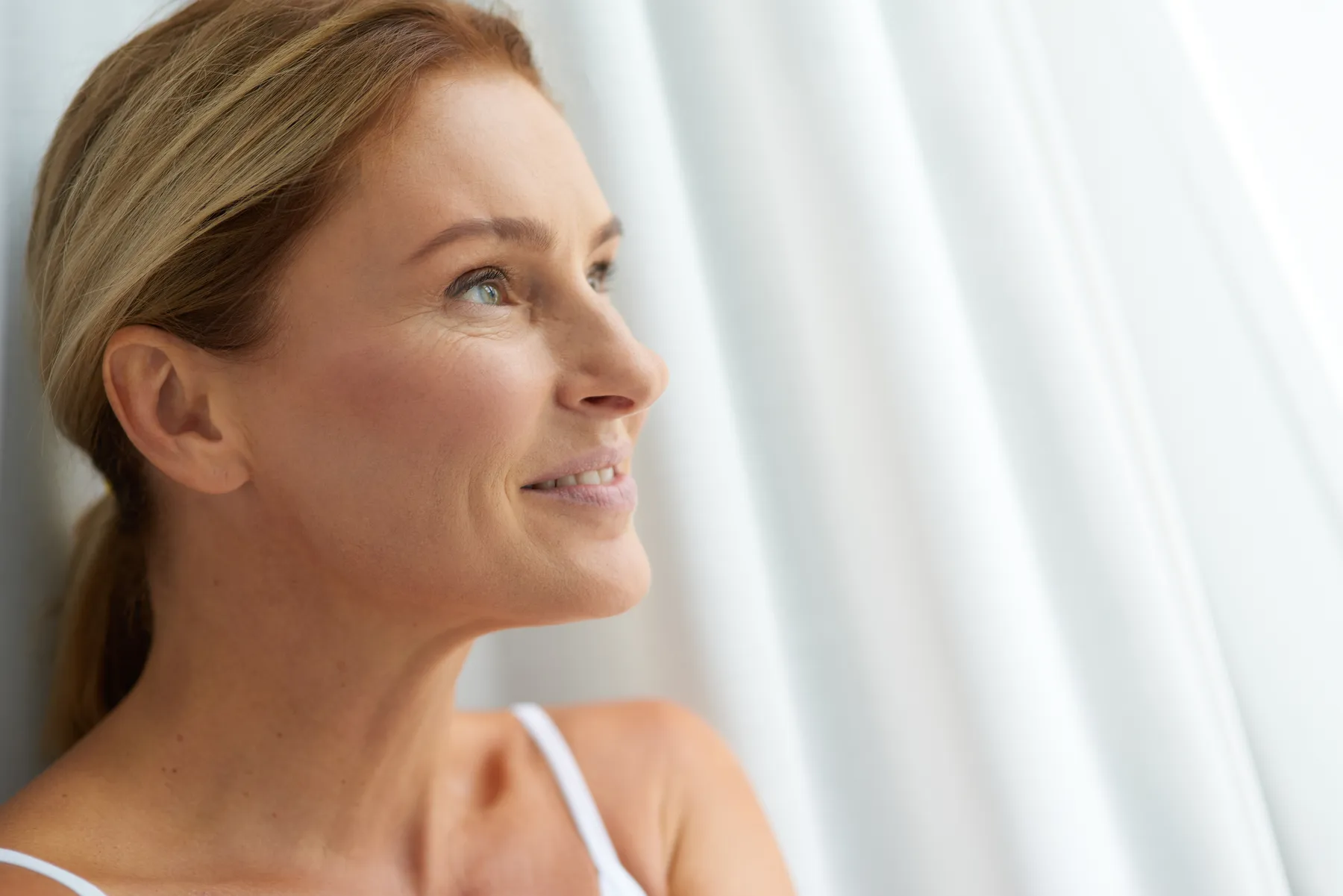 A smiling woman relaxing at home in soft light