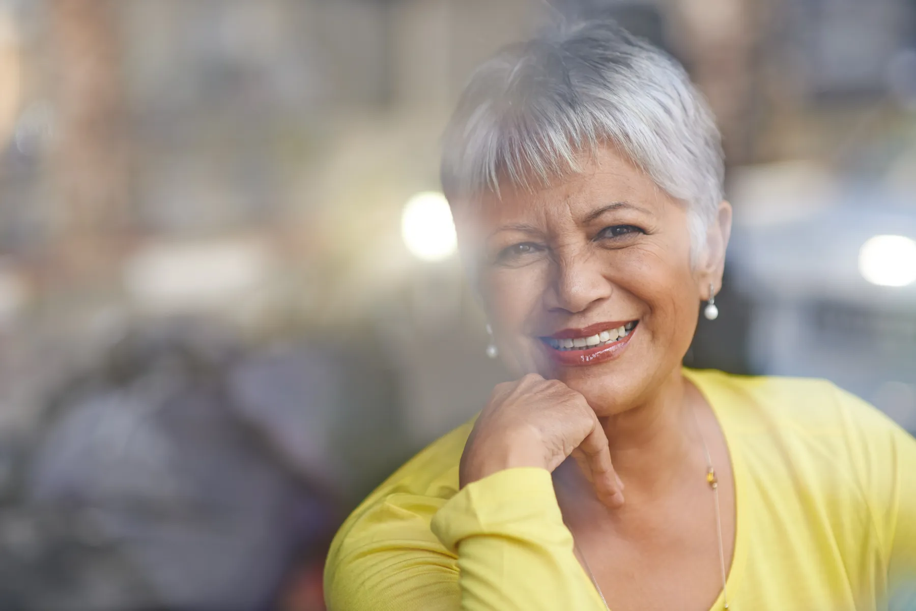 A smiling woman wearing yellow top in urban setting