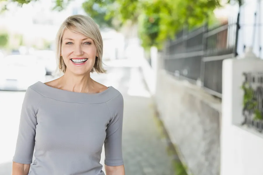 A smiling woman with blond hair outside during