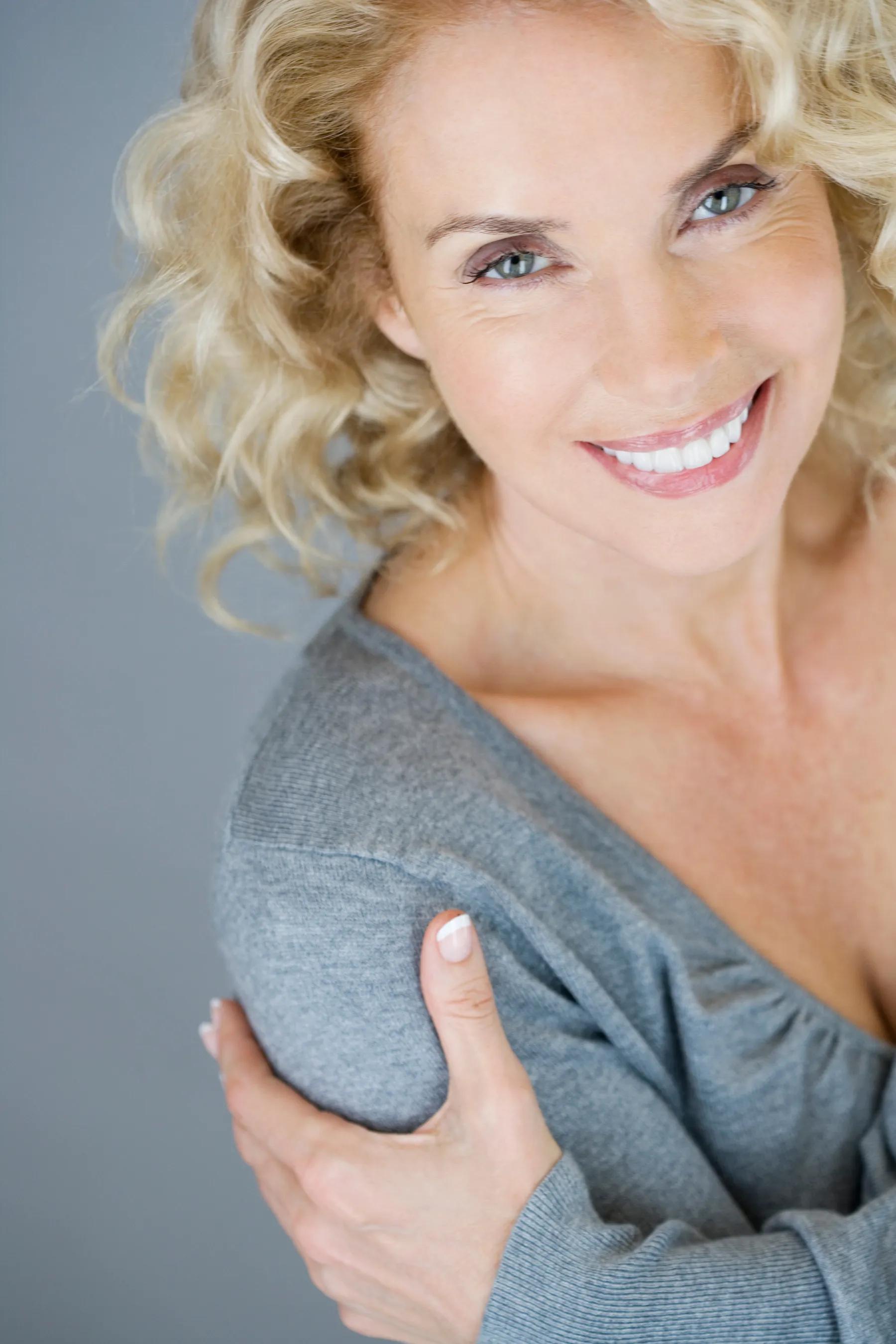 A smiling woman with blonde hair and gray shirt