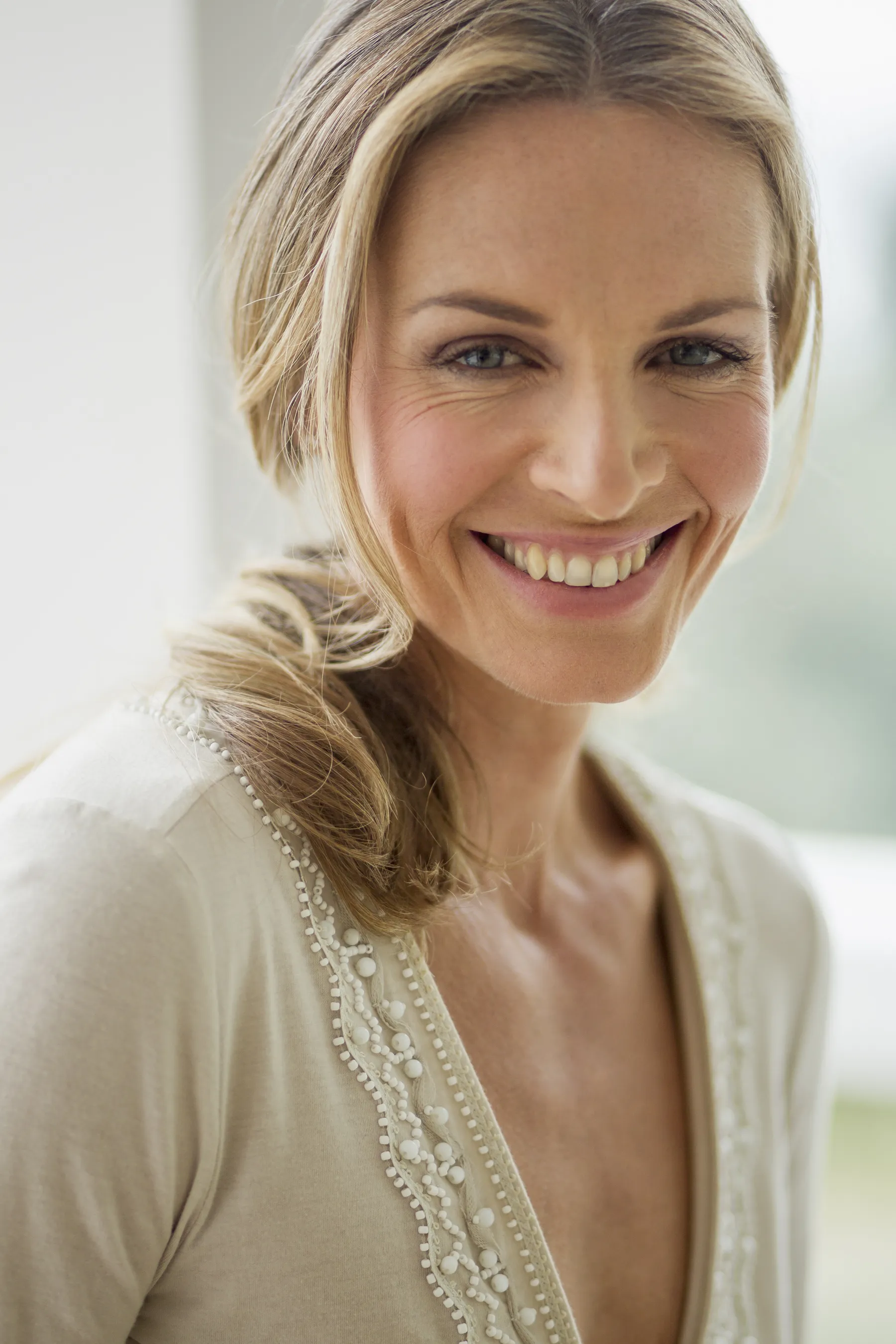 A smiling woman with blonde hair in natural light