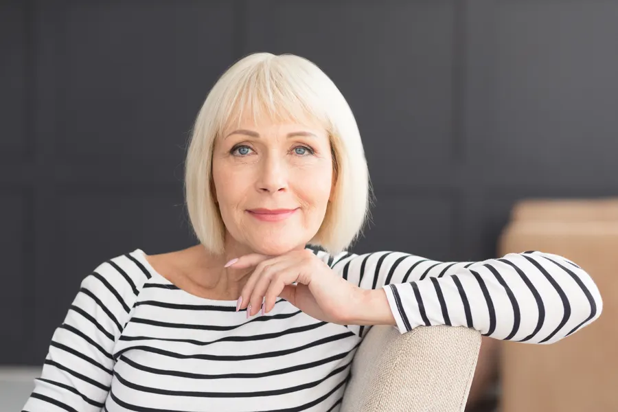 A smiling woman with blonde hair sitting indoors