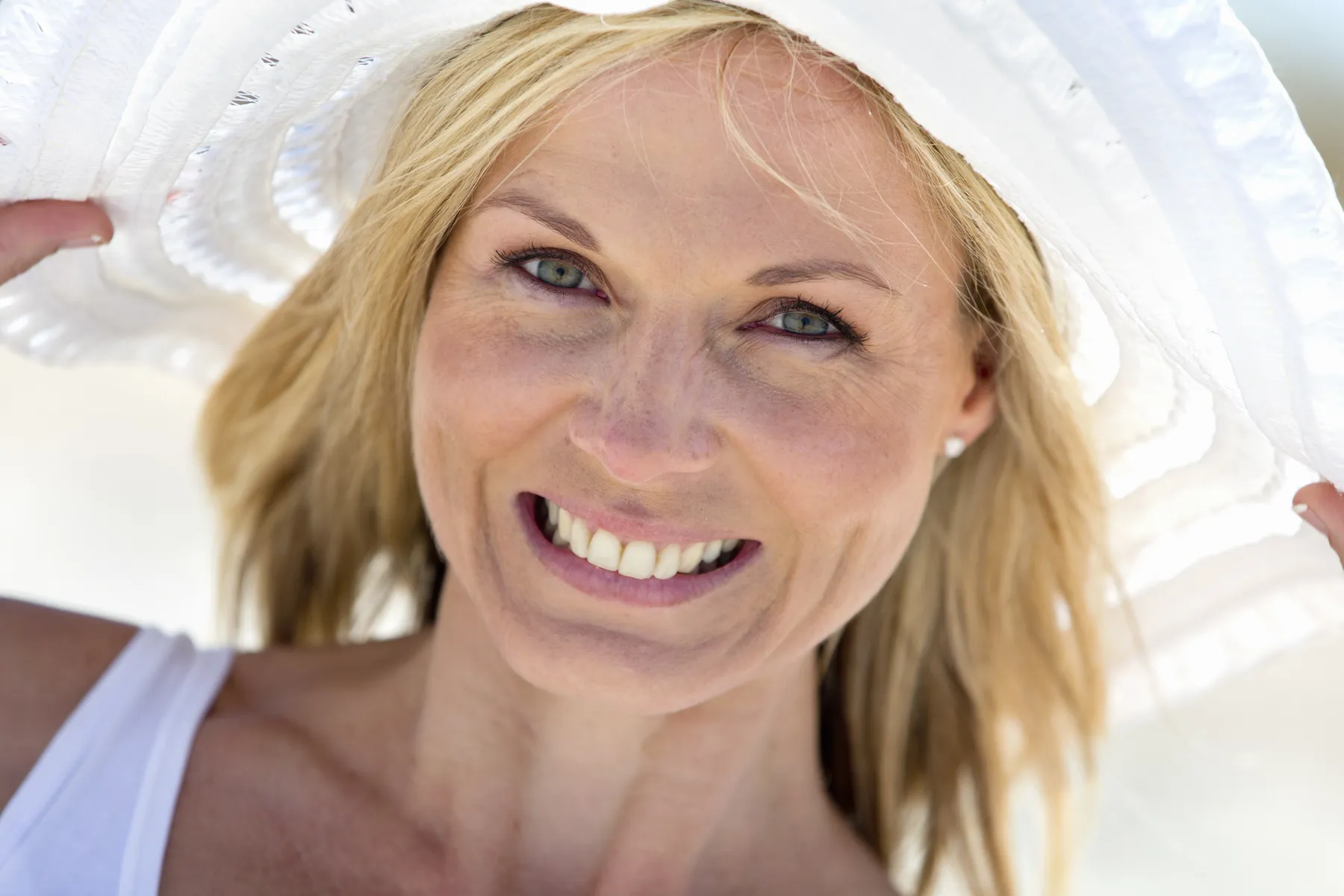 A smiling woman with blonde hair wearing a white