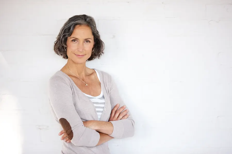 A smiling woman with crossed arms against white