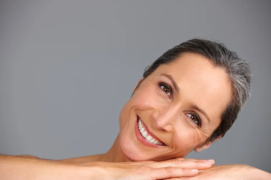 A smiling woman with gray hair leaning on hands