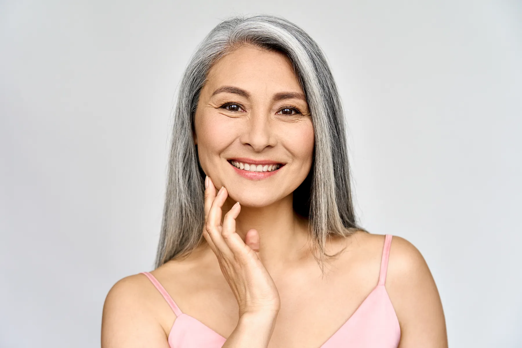 A smiling woman with gray hair posing in studio