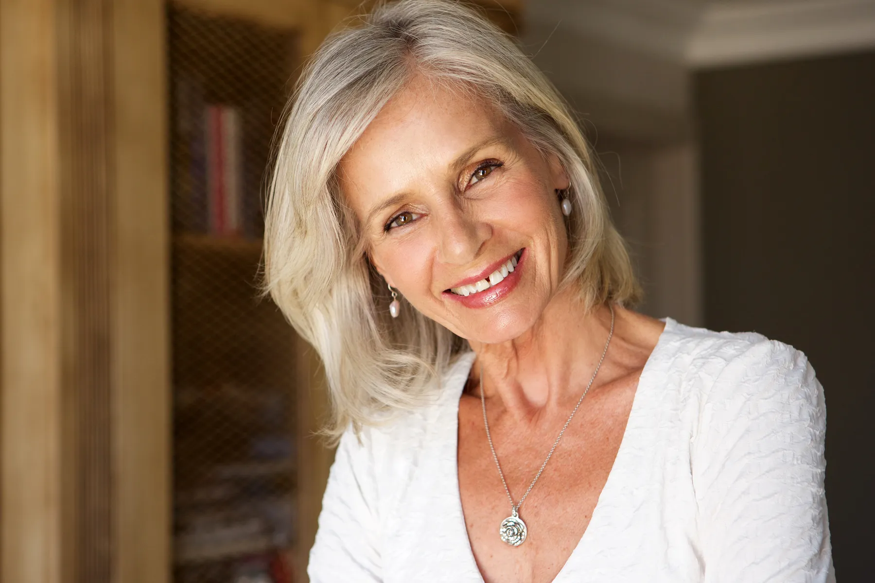 A smiling woman with gray hair wearing white