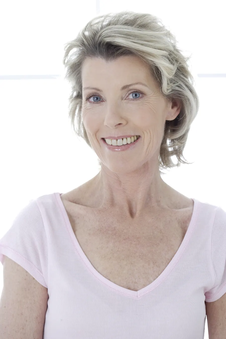 A smiling woman with grey hair in white studio