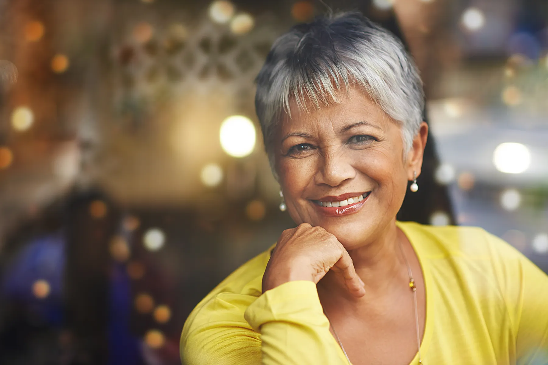 A smiling woman with grey hair posing indoors