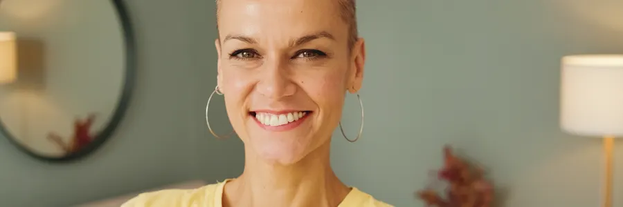 A smiling woman with very short hair indoors