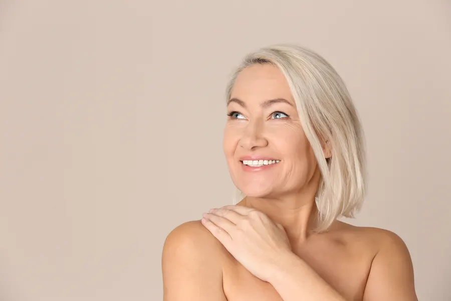 A smiling woman with white hair in studio setting