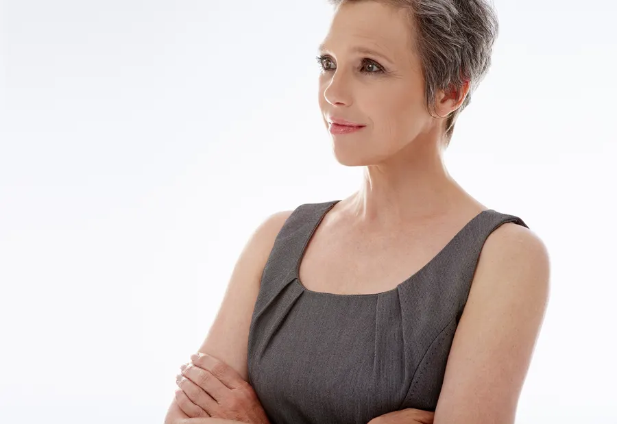A sophisticated woman in gray dress poses calmly