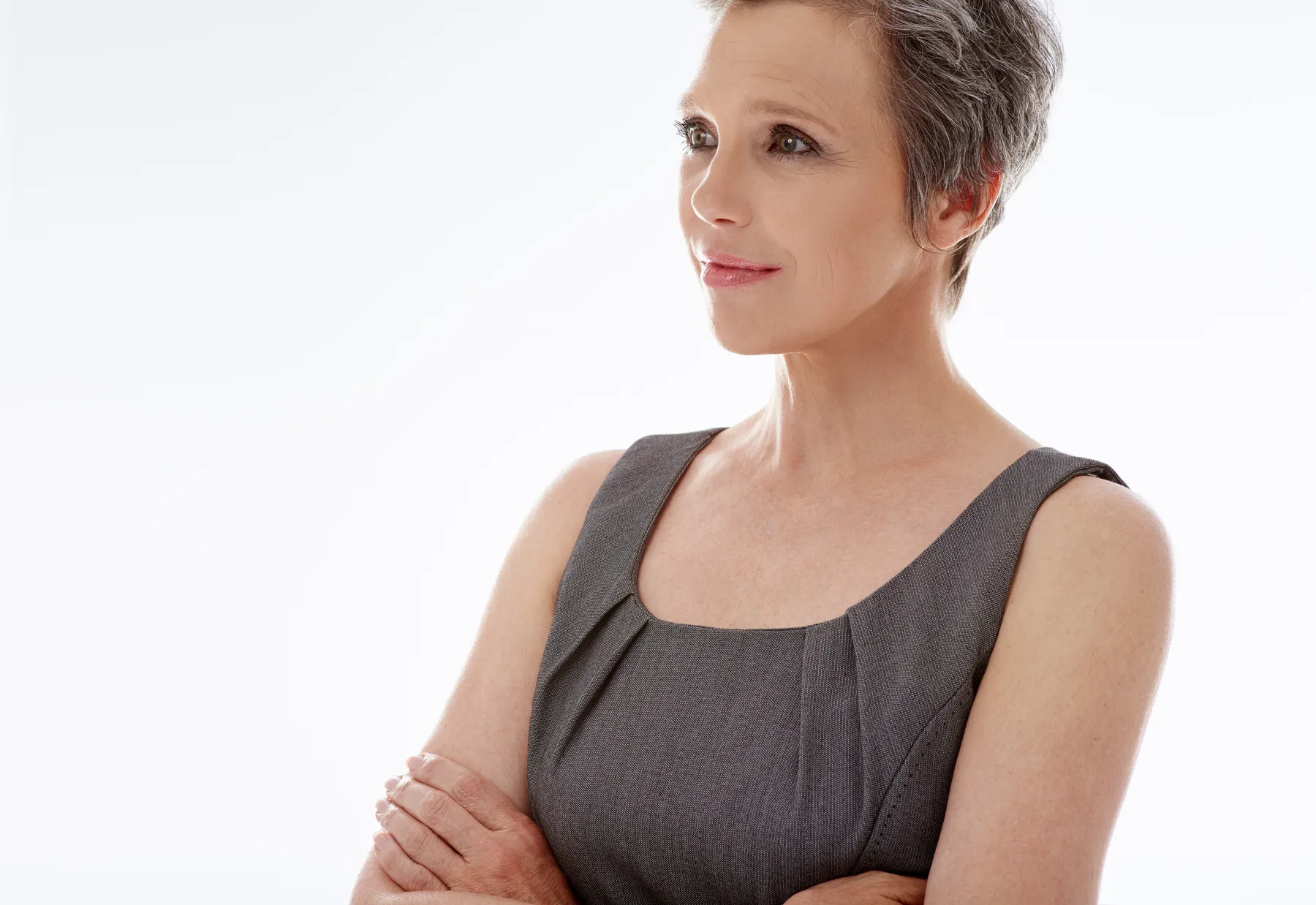 A sophisticated woman in gray dress poses calmly