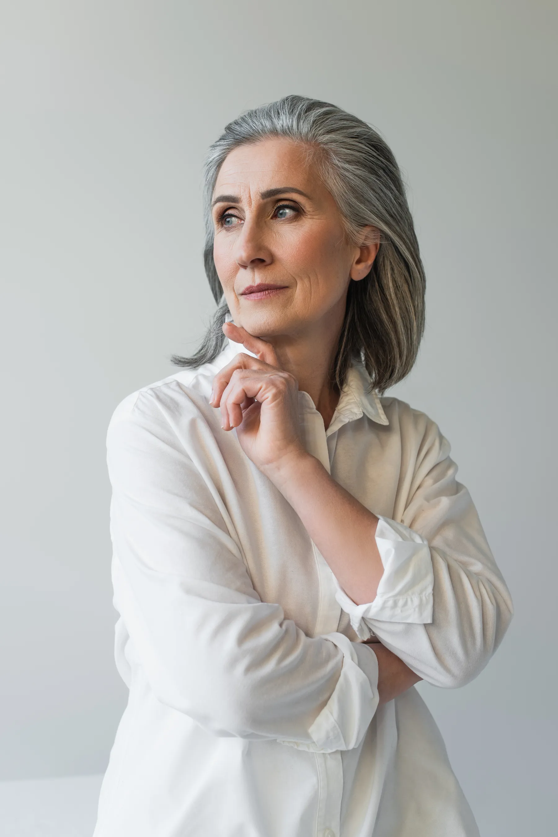 A thoughtful woman poses in white shirt indoors