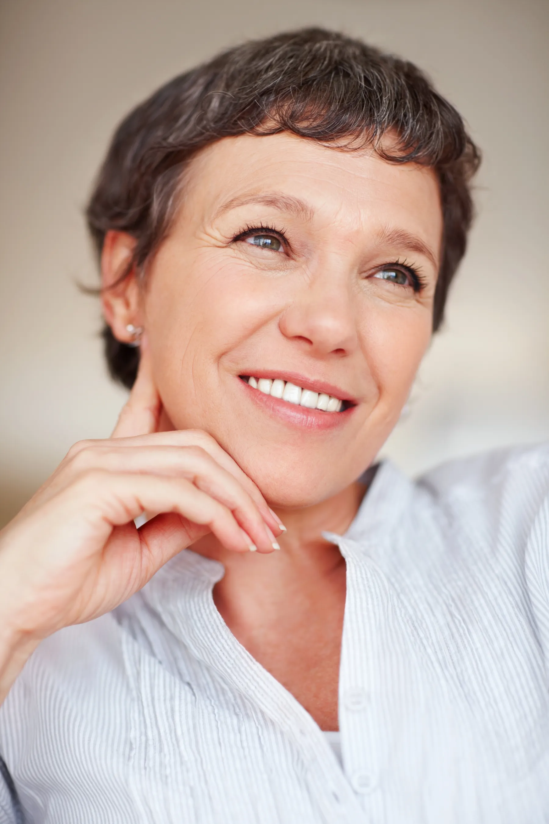 A thoughtful woman with gray hair smiling indoors