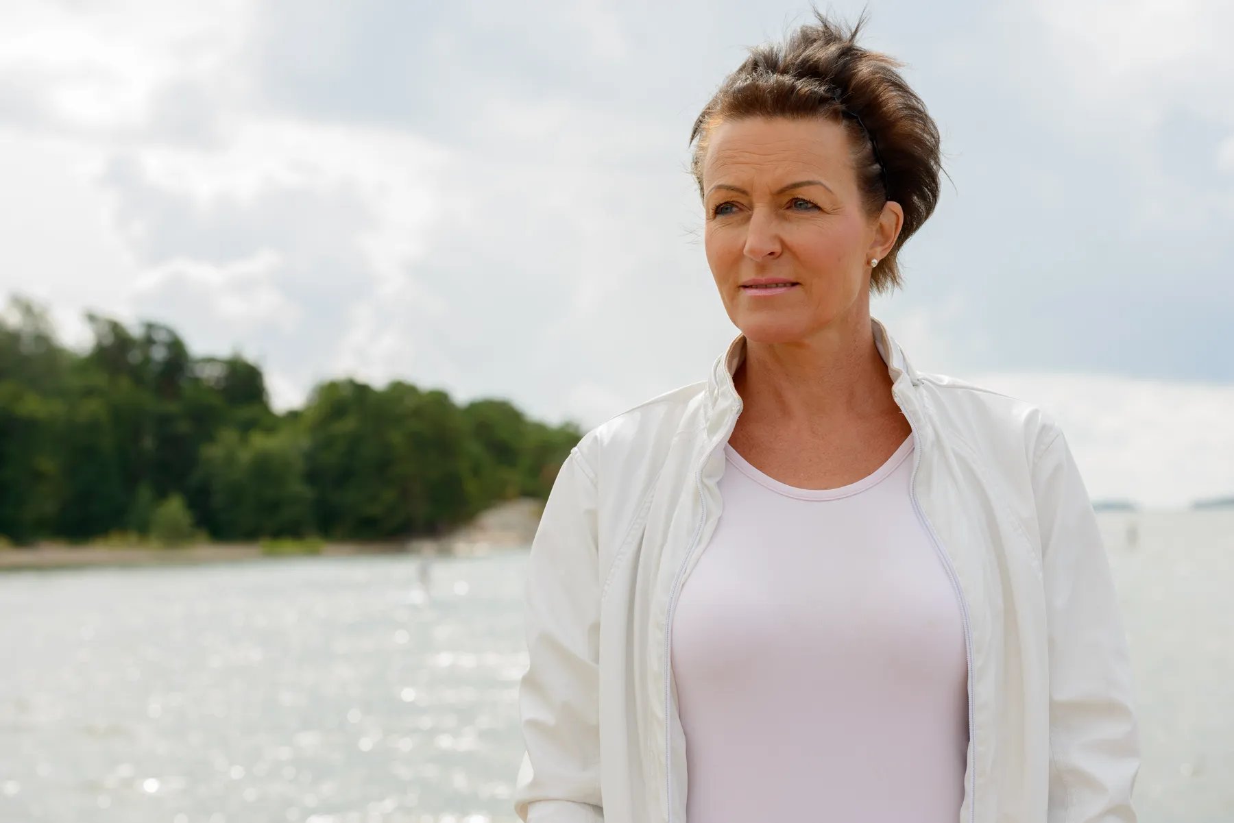A woman in jacket enjoys serene waterside vista